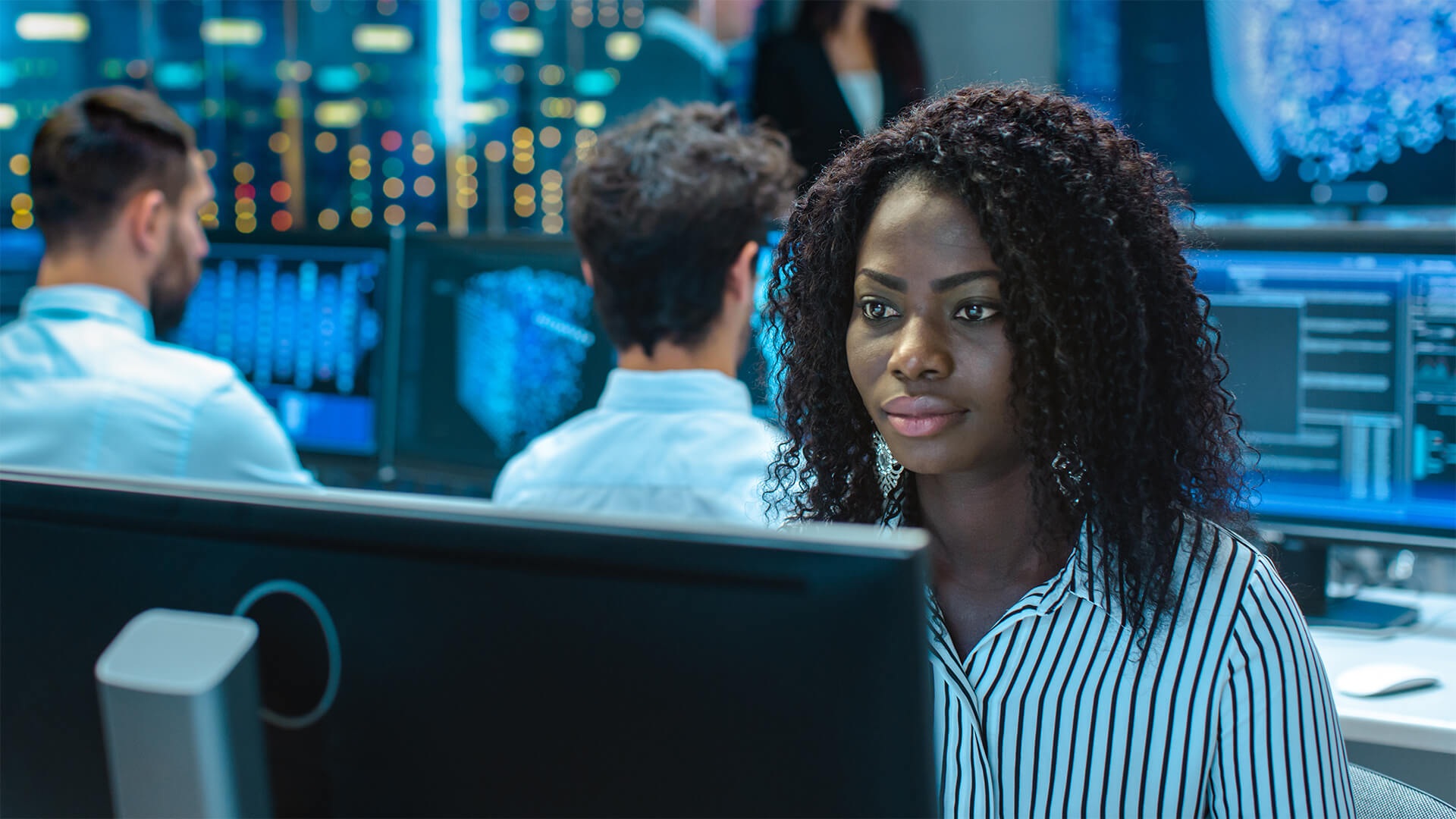 Woman working in computer engineering with co-workers behind her