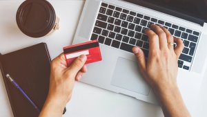 Top view of a man using a laptop while making a purchase with a business credit card