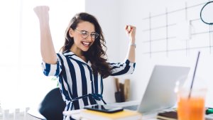 Woman sitting at her laptop celebrating business success