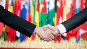 Closeup of handshake. There are flags out of focus in the background