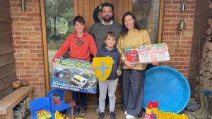 Jason and family from Young Planet holding second hand toys in front of their home