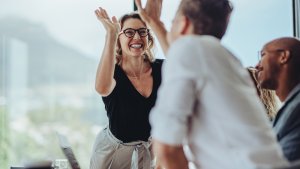 Business woman giving a high five to a colleague in meeting