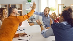 People in a meeting sitting at a table, clapping and giving each other high fives