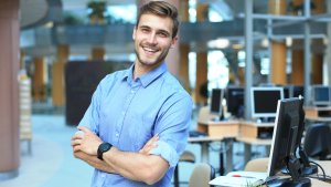 Young man posing confident and positive in professional workplace office with space.