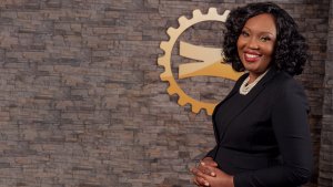 Business Woman standing in front of a brick wall with Zambia National Bank Logo