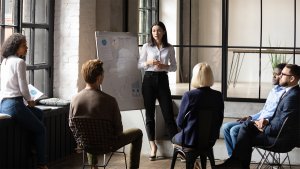 Woman Standing in Front of White Board Giving a Presentation