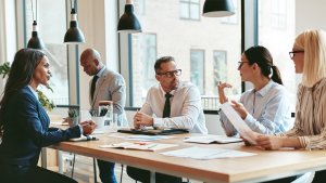 People in an office sitting by a table having a meeting