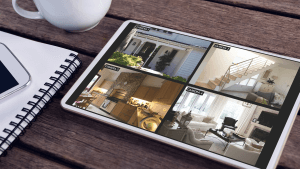 Tablet with views of home from security cameras on screen lying on wooden table