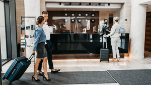 A young business couple arrives at the hotel and goes to the front desk to check in.