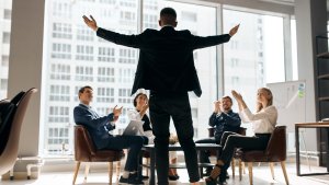 business people sitting at table congratulating colleague with promotion