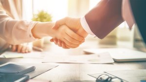 Businessman and businesswoman shaking hands above desk