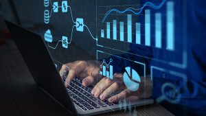 Analyst working with Business Analytics and Data Management System on computer to make report