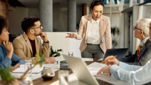 female leader using laptop and communicating with her business team during meeting in the office.