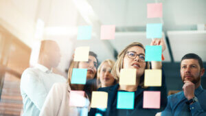 Group, team or staff discussing with sticky notes a schedule for future project together