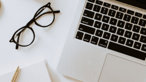 glasses laying on table next to laptop