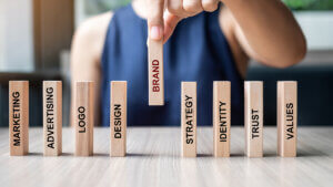 Businesswoman hand placing or pulling wooden Dominoes with BRAND text