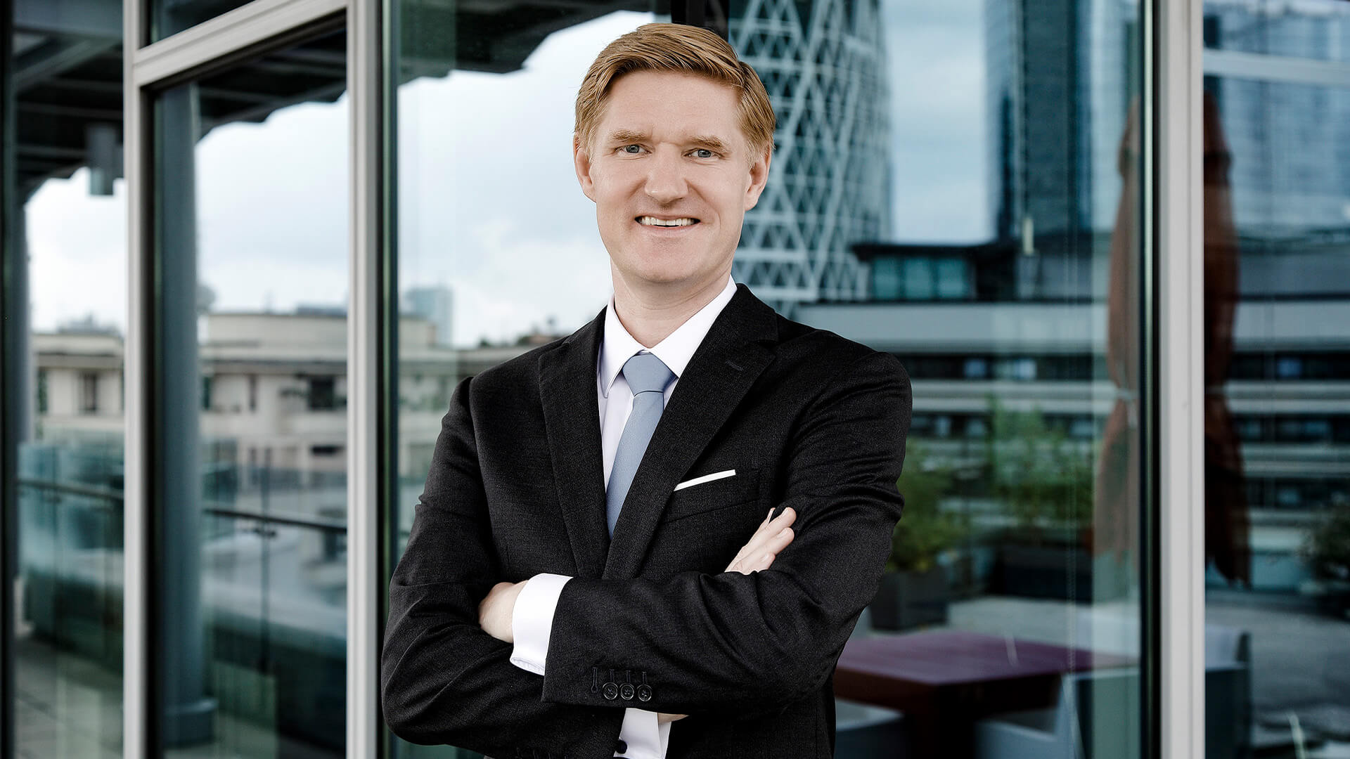 Man with arms crossed looking at camera smiling