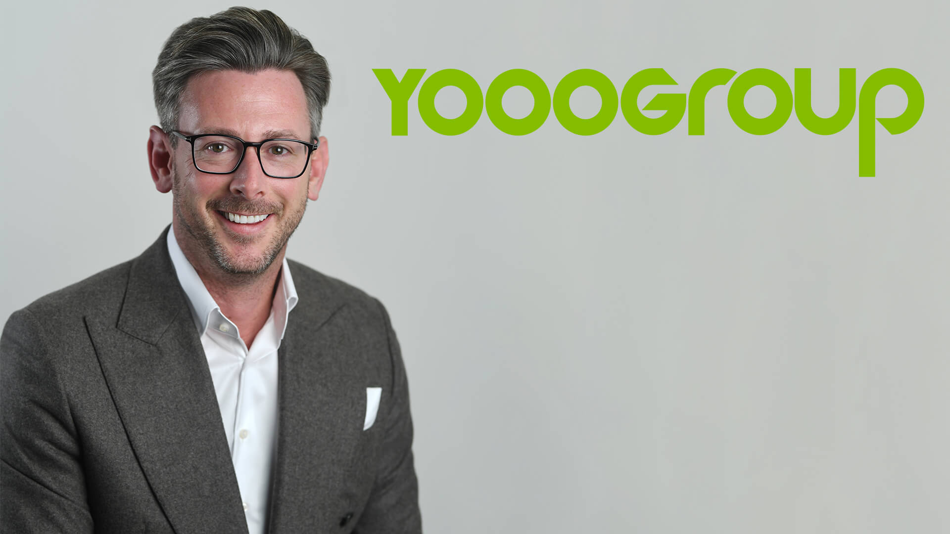 man smiling at camera with yooogroup logo next to him