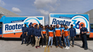 group of people standing in front of trucks smiling