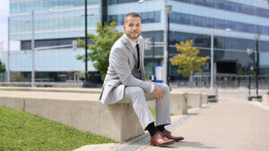 man sitting on concrete block in suit in front an office