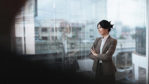 Young asian businesswoman looking out window in meeting room with confidence