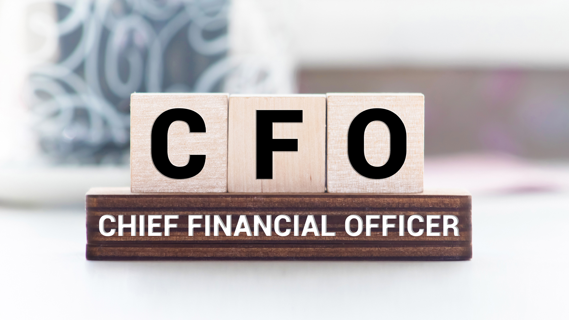 CFO Chief Financial Officer written on a wooden cube in front of a laptop