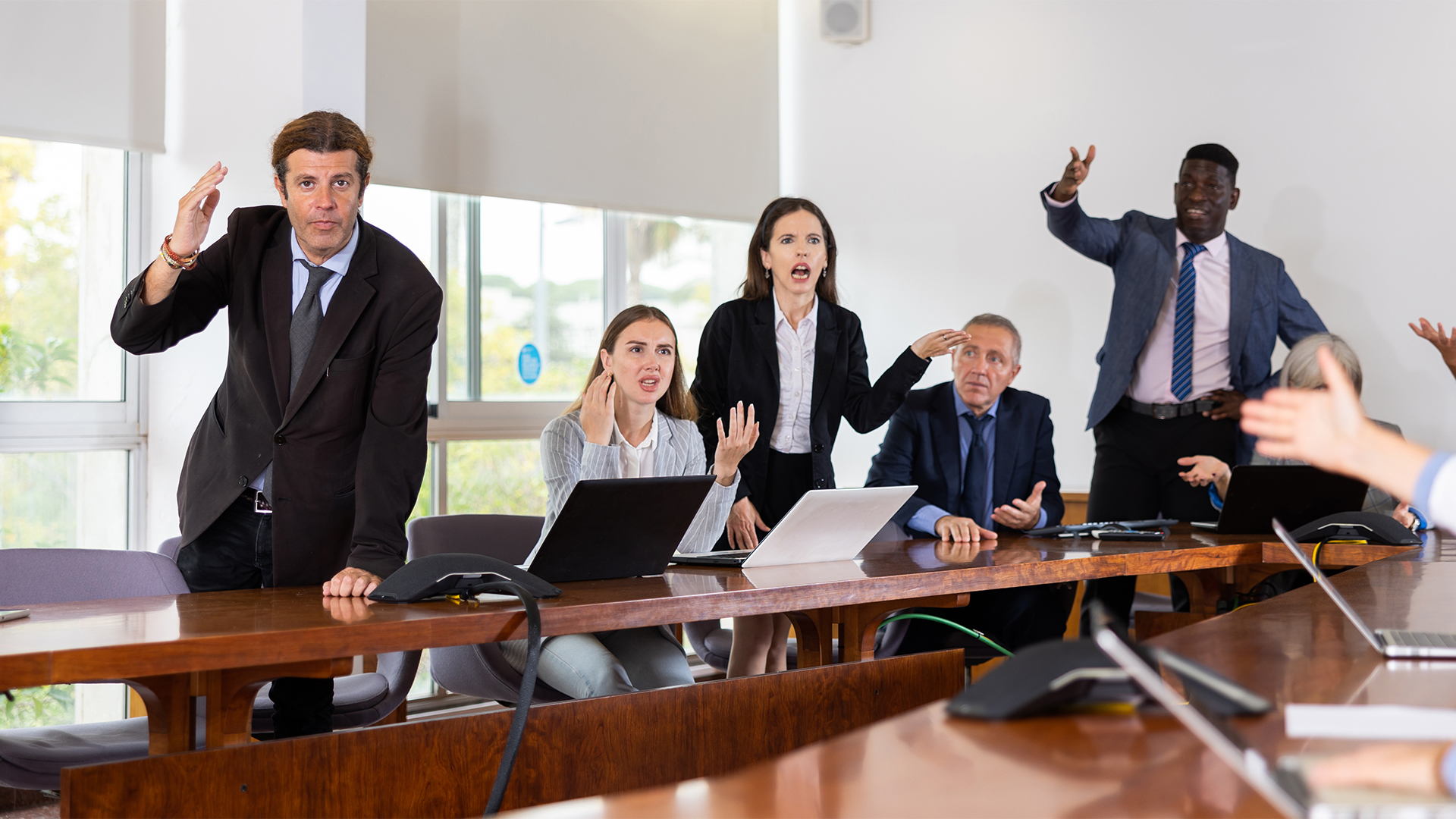 Irritated multiethnic various aged business team arguing to each other on corporate group meeting in office unable to come to a unified agreement