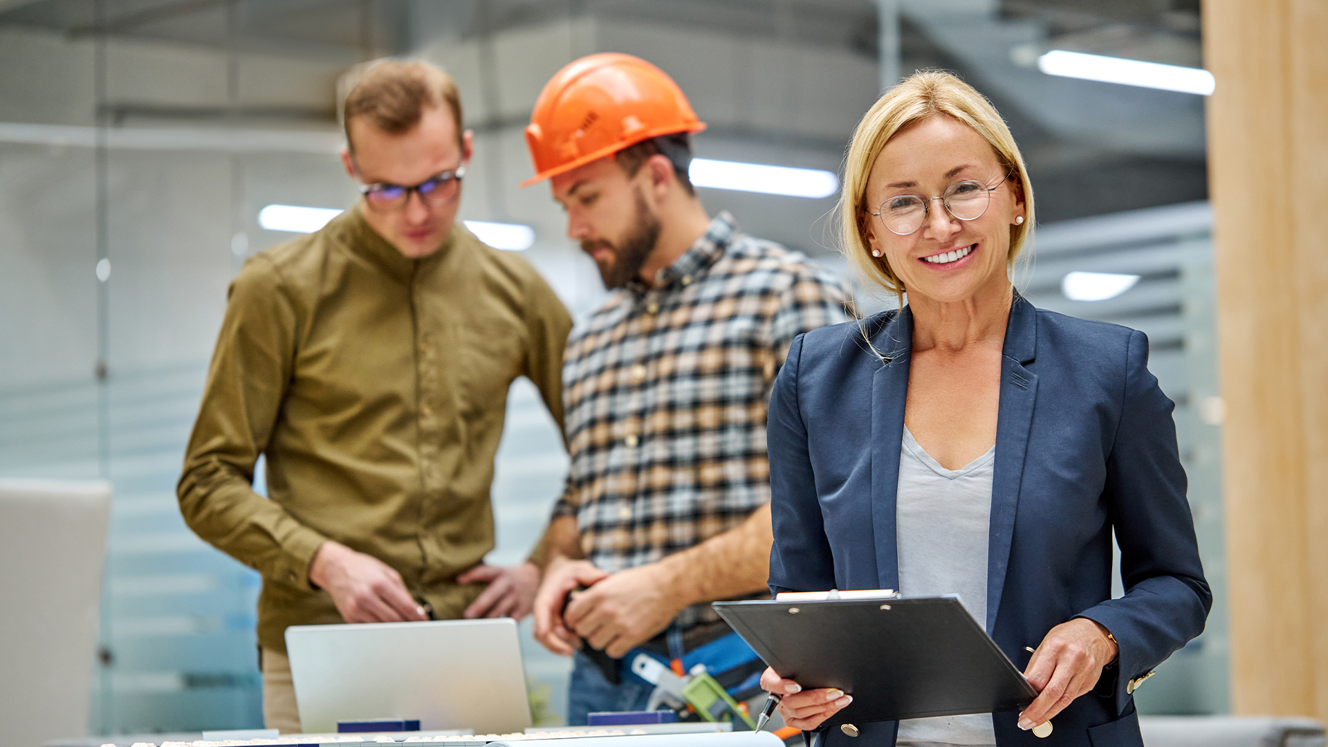 portrait of leading engineer woman in formal wear supervising the construction design process by architects concentrated on work in the background