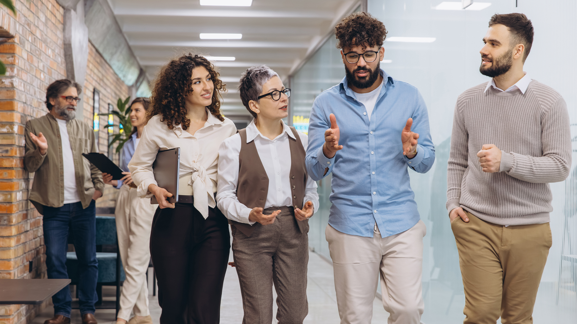 Diverse business professionals walking through office corridor, discussing work, team collaborating, and problem solving